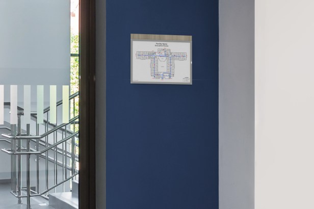 A well-designed and clearly visible Flexia Iso™ evacuation map holder displayed prominently on a wall leading to an office stairwell.