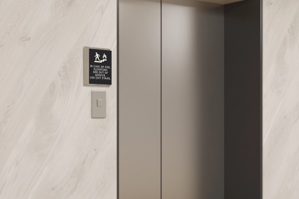 An In Case of Fire, Elevators Are Out of Service (INV-ICOF118-A) sign located next to an elevator call button.