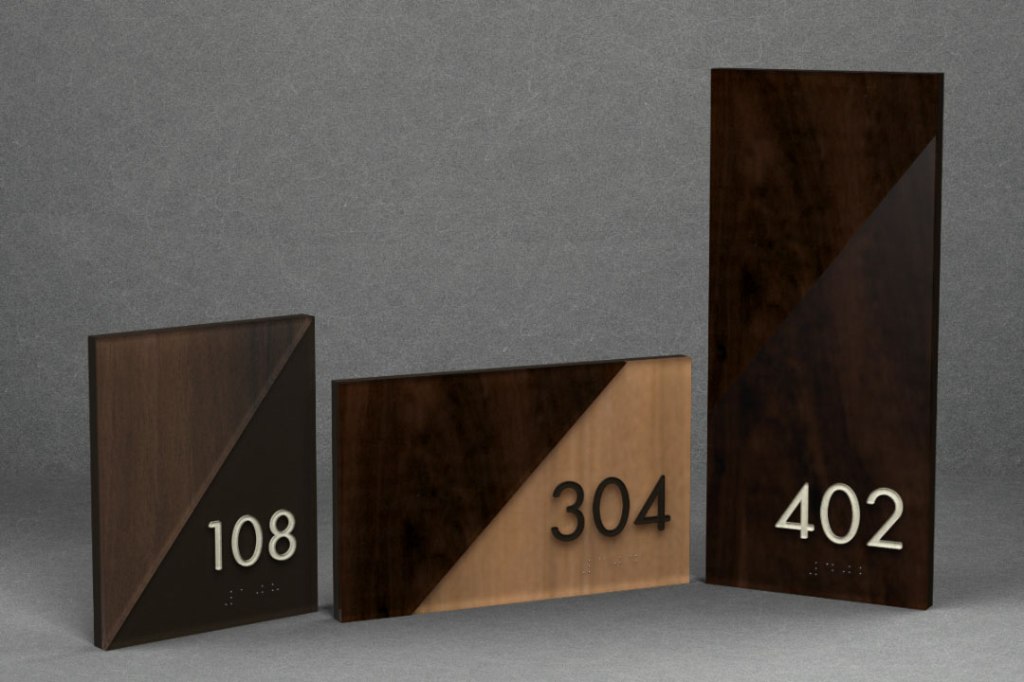 Three ADA-compliant room number signs in different sizes and wood finishes, displaying the numbers 108, 304, and 402.