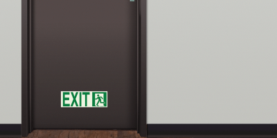 Photoluminescent Emergency Exit Sign (Left) mounted low on door marking emergency egress path.