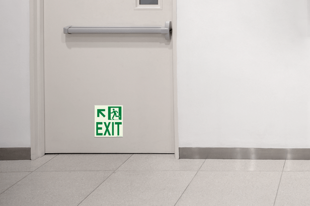 Photoluminescent Emergency Exit Sign w/Arrow (Left) mounted low on door indicating direction of egress.