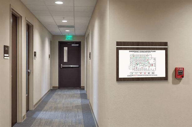 Evacuation map sign (EVP1115-AC) mounted in office corridor showing exit routes for emergency egress guidance